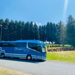 Autobús grande en color azul con logotipo rotulado y fonde de Parque do Gozo